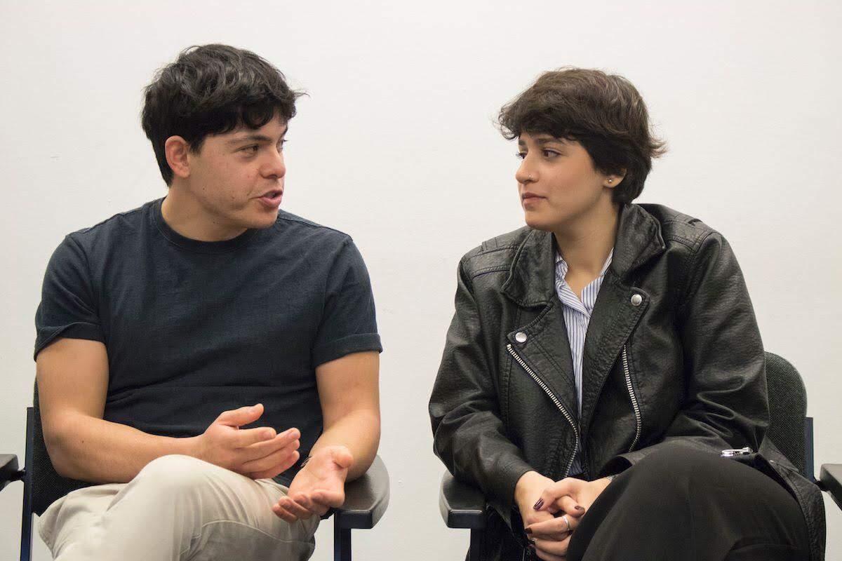 Seán and Sara sit and have a conversation against a white background.